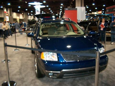 2001 Ford Crown Victoria - A blue SUV is on display at an indoor event, with its rear cargo area accessible.