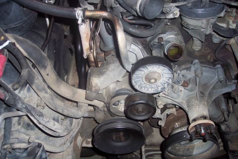 1995 Ford Bronco - This is a close-up, detailed view of the engine bay of a 1995 Ford Bronco, focusing on the serpentine belt system and pulleys. The image hi…