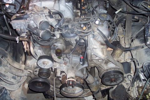 1995 Ford Bronco - A close-up view of a dirty engine bay, likely from a 1995 Ford Bronco, showing various engine components, hoses, and wiring.