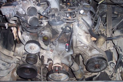 1995 Ford Bronco - This is a close-up, overhead view of a complex engine bay, likely from a 1995 Ford Bronco. The image focuses on the water pump, pulleys, ho…