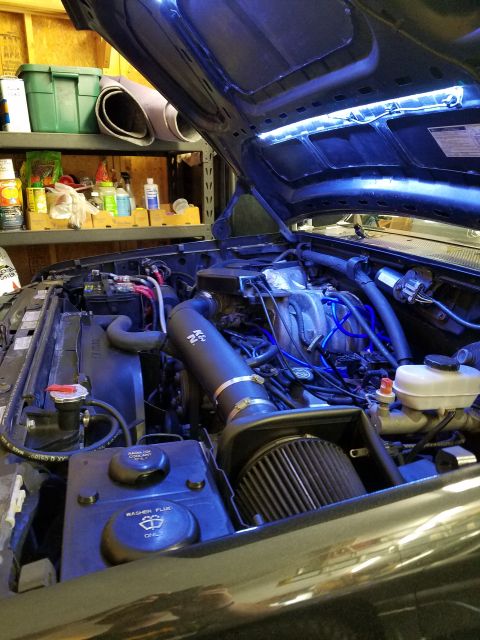 1995 Ford Bronco - The engine bay of a dark colored vehicle, likely a Ford Bronco, is illuminated by blue LED lights under the hood. Visible modifications inc…