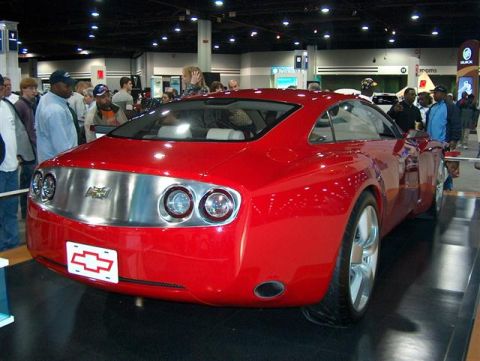 2001 Ford Crown Victoria - A red concept car is displayed at an auto show, a distinctive rear design with chrome accents and Chevrolet badging.