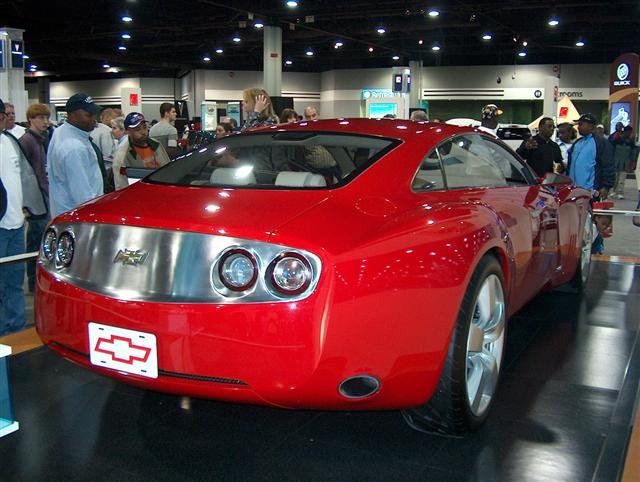 Red concept car rear view with chrome strip, dual round taillights, and Chevrolet emblem