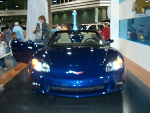2001 Ford Crown Victoria - A blue convertible sports car is displayed with its doors open at an auto show.