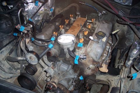 1995 Ford Bronco - This is a top-down view of a V8 engine bay with fuel injectors and various hoses labeled with blue tape and numbers. A wooden plank is plac…