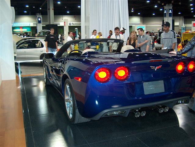 Blue convertible sports car with quad exhaust pipes and distinctive taillights on display