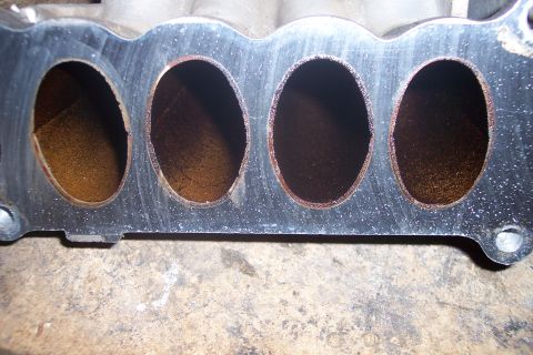 1995 Ford Bronco - This is a close-up view of the intake manifold ports of a vehicle. The ports are oval-shaped and show signs of carbon buildup.