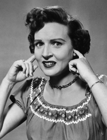 1967 Ford Custom Wagon - A black and white studio portrait of actress Betty White covering her ears with her fingers.
