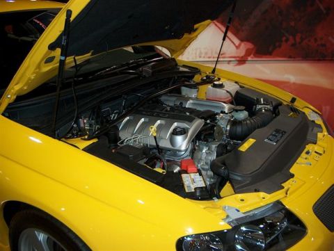 2001 Ford Crown Victoria - The engine compartment of a yellow car is displayed with the hood raised.