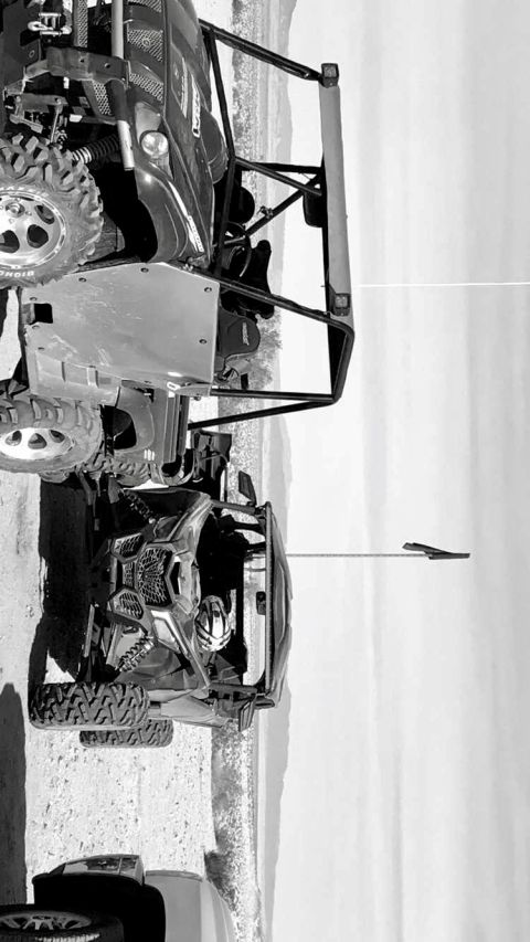 1988 Ford Bronco - Two off-road vehicles, a buggy and an SUV, are parked side-by-side on a dirt lot with a distant mountain range.