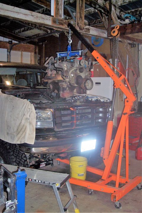 1995 Ford Bronco - An engine hoist lifts an engine out of a Ford truck, which appears to be from the early to mid-1990s.