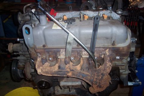 1995 Ford Bronco - A close-up view of a V8 engine's cylinder head and exhaust manifold, showing spark plugs, fuel injectors, and various metal components. The…