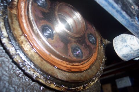 1995 Ford Bronco - This close-up shows a rusty metal flange with visible bolts and an orange gasket, likely a vehicle part.