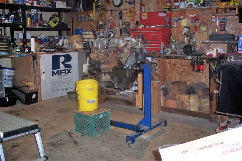 1995 Ford Bronco - An engine is mounted on a blue stand in a workshop, surrounded by tools and supplies.