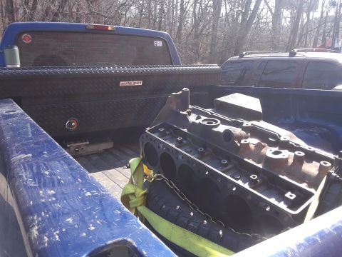 1985 Ford Bronco - A disassembled engine block is secured with straps and chains in the bed of a pickup truck.