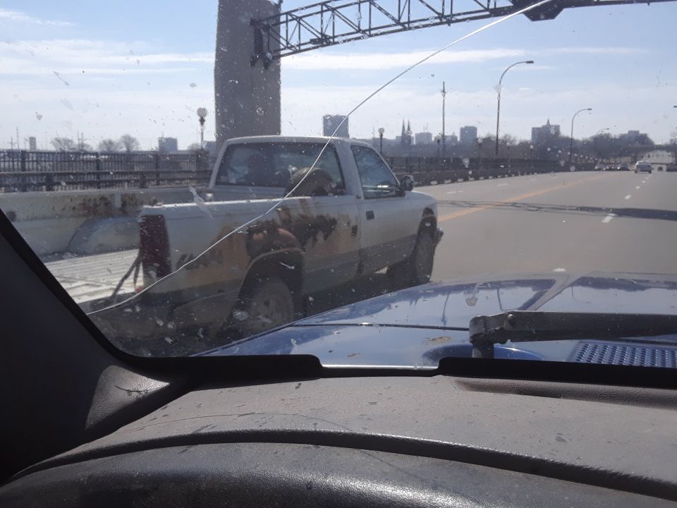 Side view of a rusty pickup truck on a highway