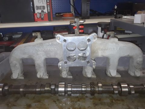 1985 Ford Bronco - Engine parts, specifically an intake manifold and camshaft, are laid out on a workbench.