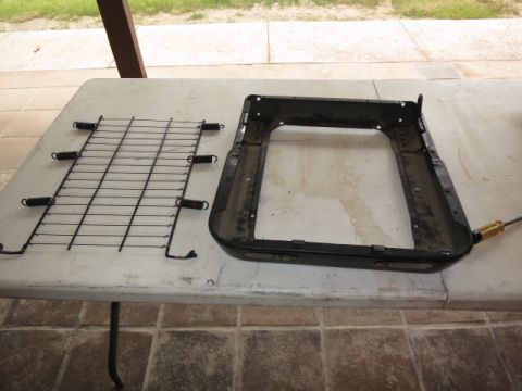 1991 Ford Bronco - A disassembled car seat frame and a separate seat spring assembly are laid out on a table.