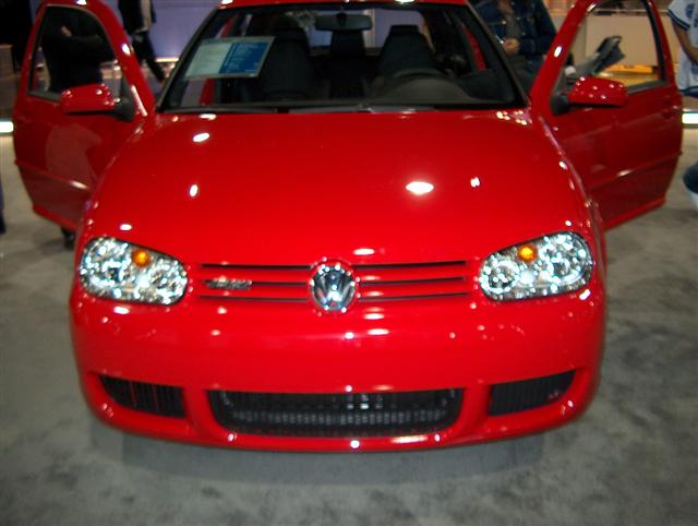 Front view of a red Volkswagen Golf GTI with doors open. Has a sticker on the windshield