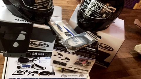 1988 Ford Bronco - Boxes of HJC motorcycle helmets and radio communication parts are laid out on a wooden floor.