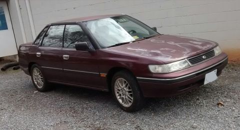1994 Subaru Legacy - This maroon 1994 Subaru Legacy sedan is shown from a 3/4 front angle, parked outdoors.
