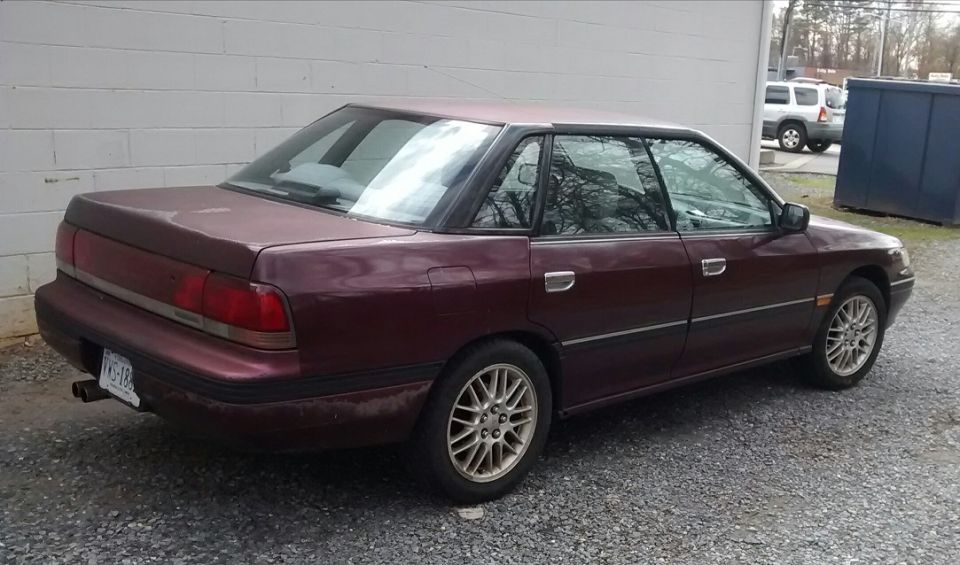 Maroon 1994 Subaru Legacy sedan, rear three-quarter view, parked outdoors