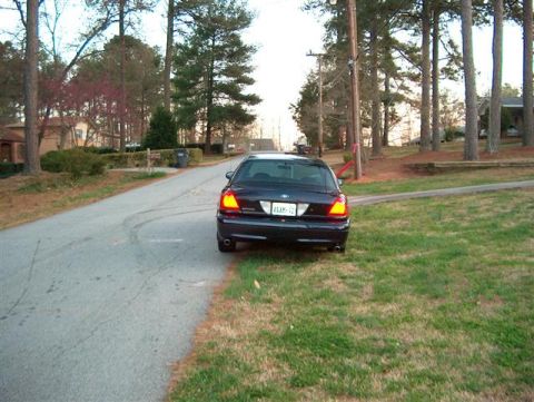 2001 Ford Crown Victoria - A dark blue 2001 Ford Crown Victoria is parked on the side of a street in a residential area.
