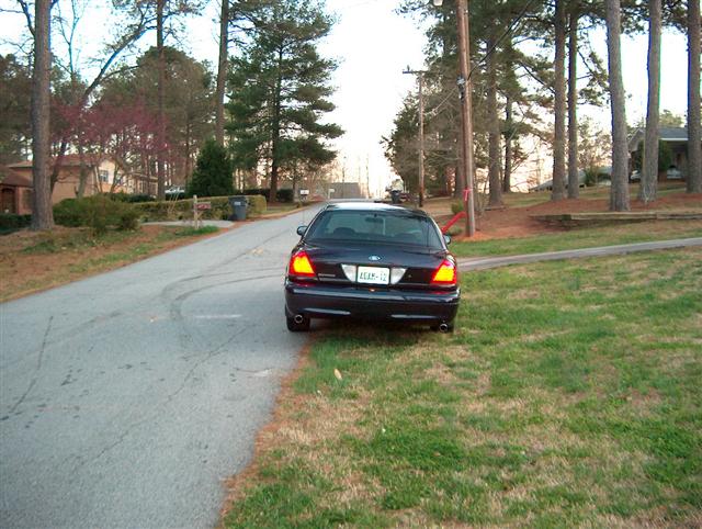 Dark blue 2001 Ford Crown Victoria parked on the right side of a residential street, rear view