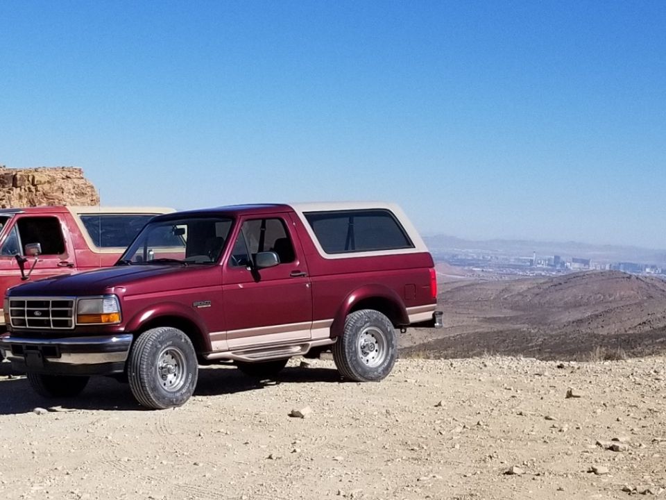 Red 1992 Ford Bronco with tan top parked on a rocky hill