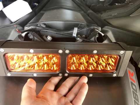 1988 Ford Bronco - A hand is positioned below a dual amber LED light bar, with wiring and mounting hardware visible.
