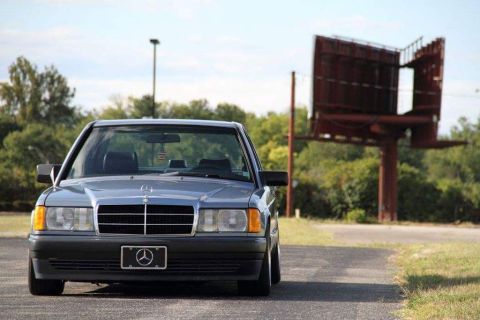 1995 Ford Bronco - Front view of a gray Mercedes-Benz sedan parked on a road with a billboard in the background.