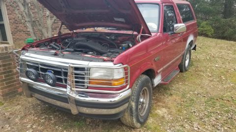 1995 Ford Bronco - This 1995 Ford Bronco is parked outside with its hood up, revealing the engine compartment.