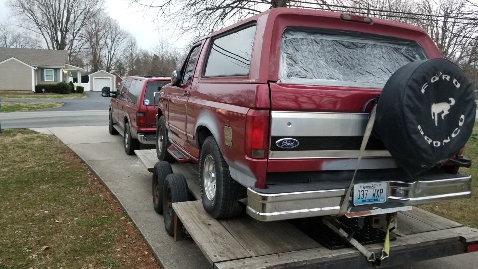 Red Ford Bronco on a trailer, another SUV behind it
