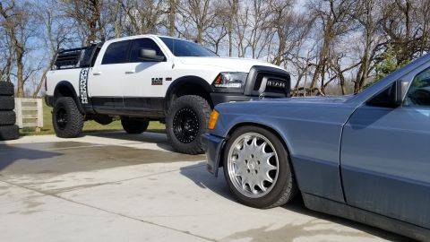 1995 Ford Bronco - A white Ram pickup truck and a blue Mercedes-Benz sedan are parked side-by-side on a concrete driveway.