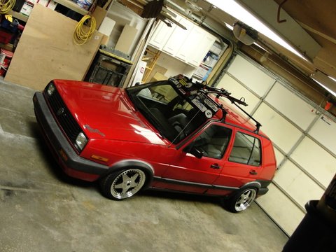 1995 Ford Bronco - Red 1990s Volkswagen Golf hatchback with a roof rack is parked inside a garage.