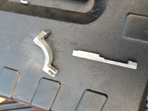 1967 Ford Bronco - Two metal automotive parts are shown on a black textured surface.