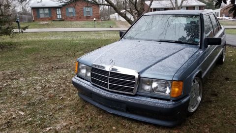 1995 Ford Bronco - A blue Mercedes-Benz sedan is parked on a grassy lawn in front of a brick house.