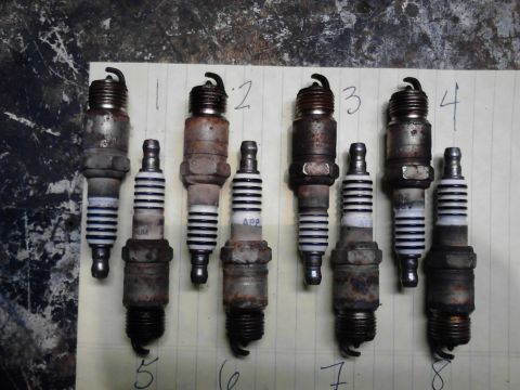 1995 Ford Bronco - Seven used spark plugs are displayed, numbered 1 through 7, on a piece of paper.