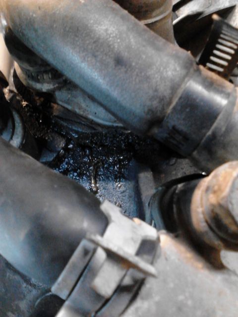 1995 Ford Bronco - Visible engine oil leak with black sludge accumulation around hoses and clamps.