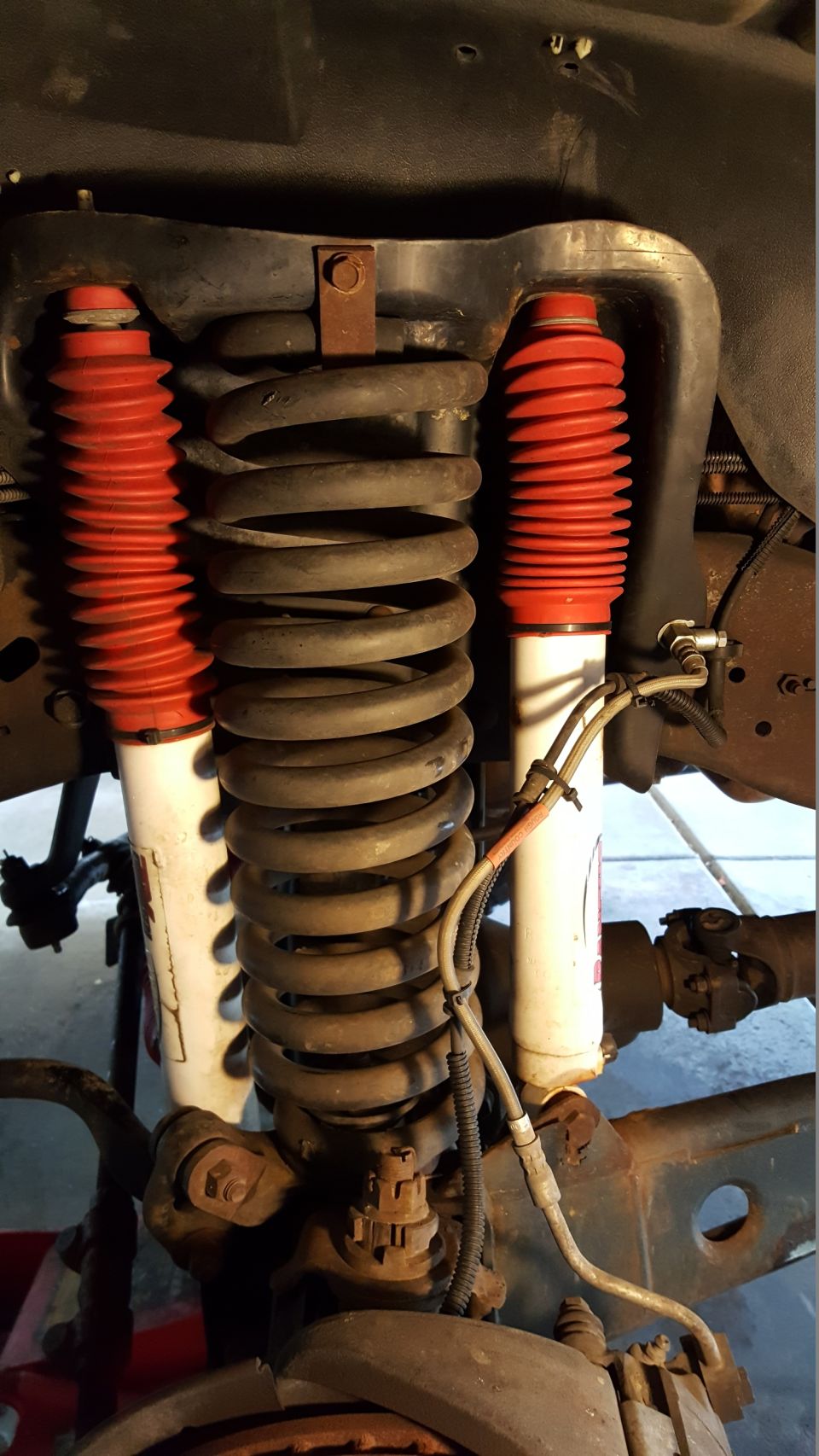 Front suspension with red-booted shocks and large coil springs. Drivetrain components visible