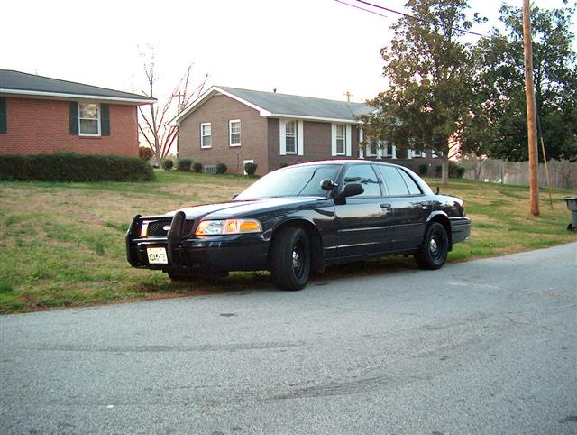 Black 2001 Ford Crown Victoria with push bar parked on street