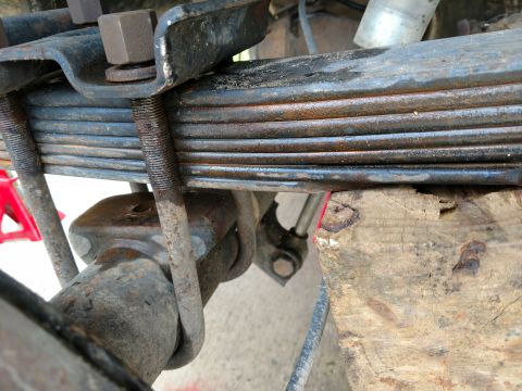 1992 Ford Bronco - Close-up view of a vehicle's leaf spring suspension system, showing its rusty U-bolt assembly.