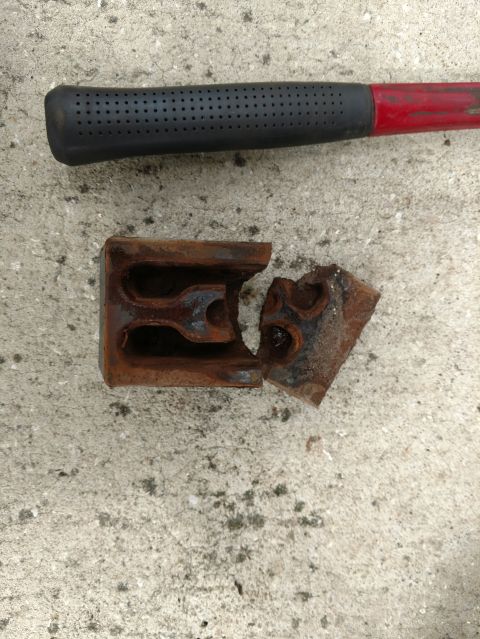 1992 Ford Bronco - A broken axle wedge lies on concrete next to a hammer handle, indicating a mechanical failure.