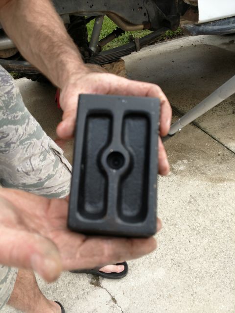 1992 Ford Bronco - Close-up of a black rubber suspension bump stop being held, with part of a vehicle's undercarriage in the background.