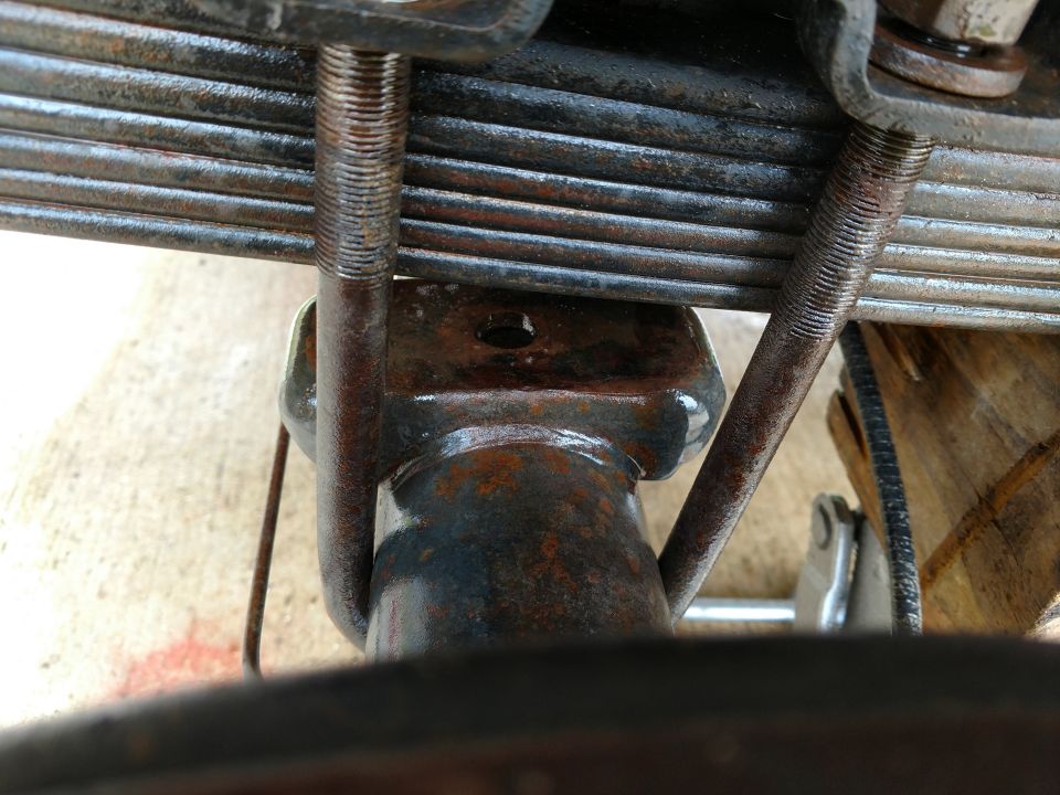 close-up of rusty leaf spring and U-bolts on vehicle axle
