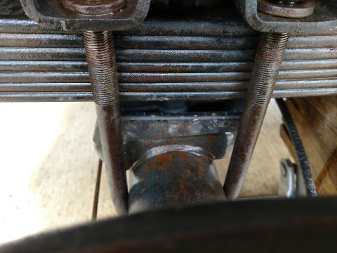 1992 Ford Bronco - Close-up view of a vehicle's leaf spring and U-bolt assembly, showing signs of rust and wear.
