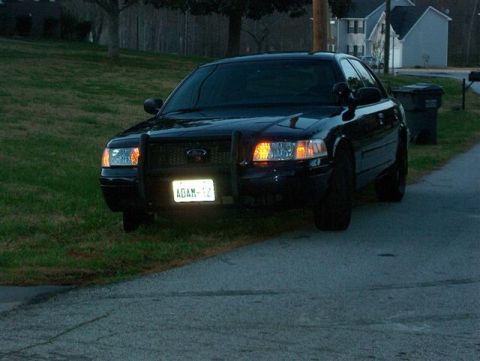 2001 Ford Crown Victoria - A black 2001 Ford Crown Victoria is parked on the side of the road with a push bar on the front.