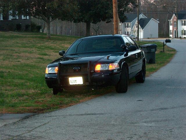 Black 2001 Ford Crown Victoria with a push bar, parked on a residential street