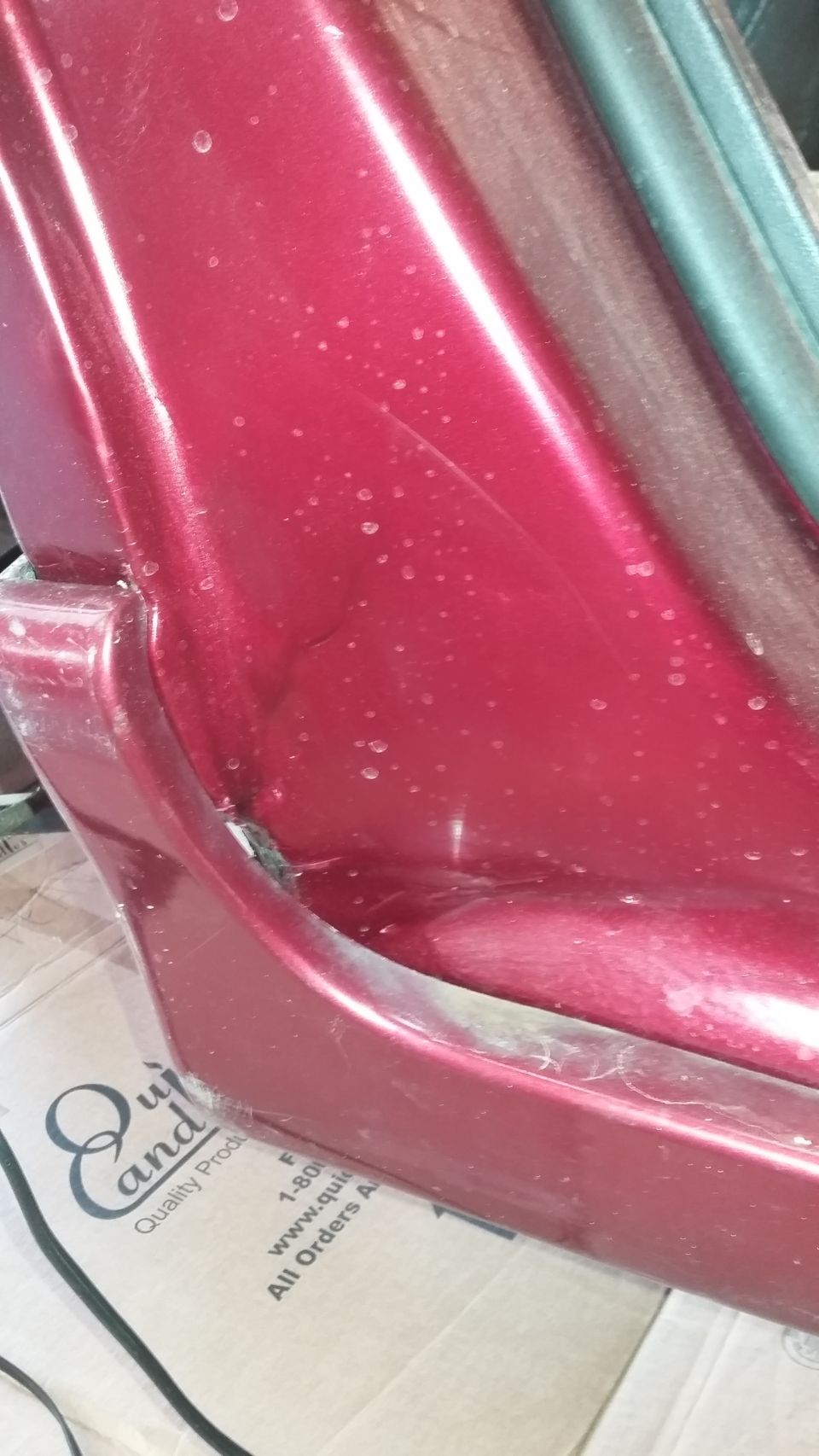 Red car door panel with visible damage and water spots. Text on box reads 'Quality Products'