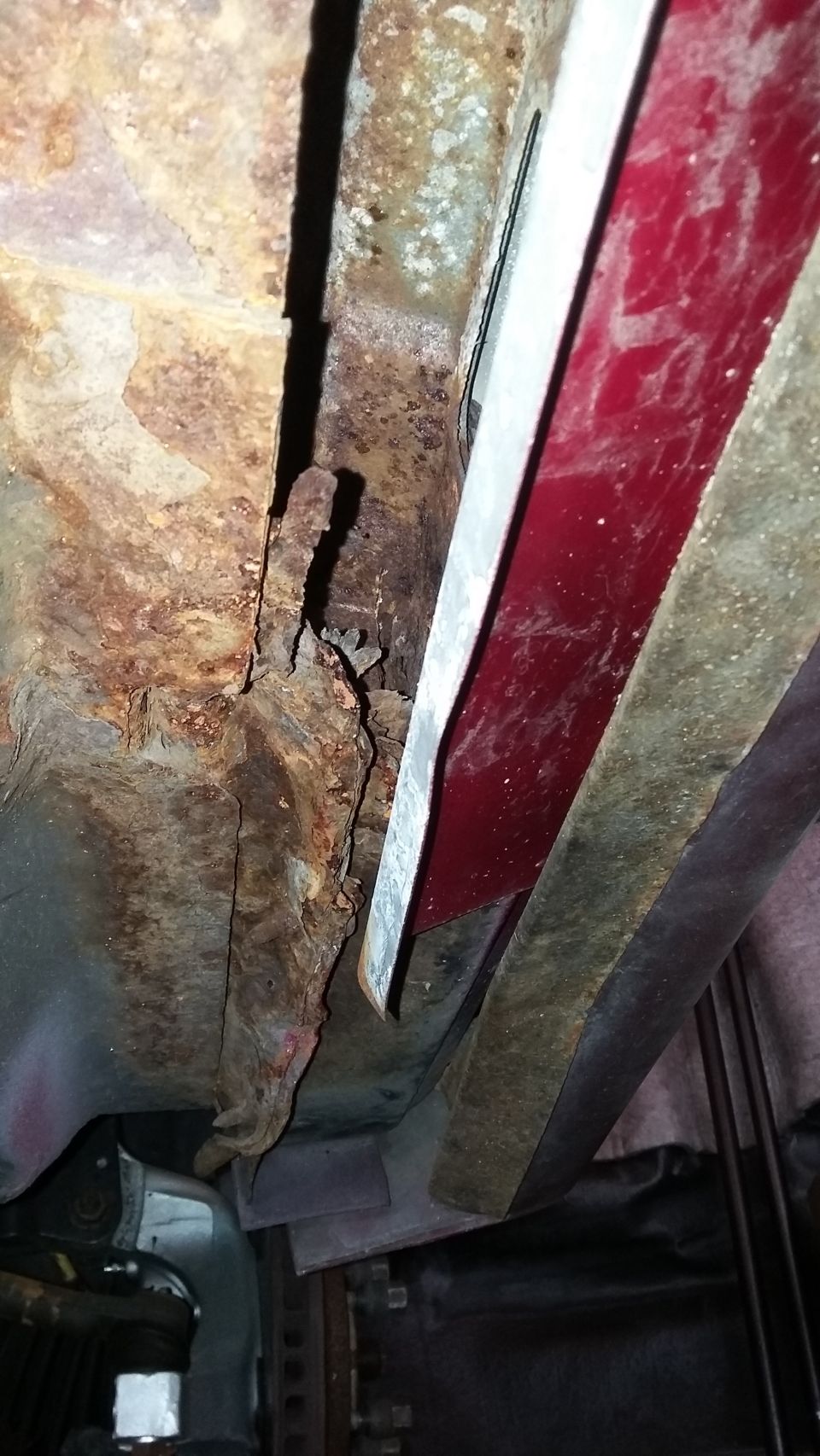Severe frame rust and rot on the underside of a vehicle